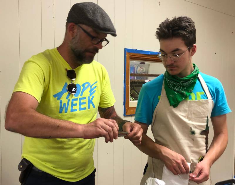 Hope Week volunteers Zach Neitzel (left) and Samuel Dickey (right) prep to paint the Putnam County Community Center by cutting plastic sheets on Wednesday, June 8.