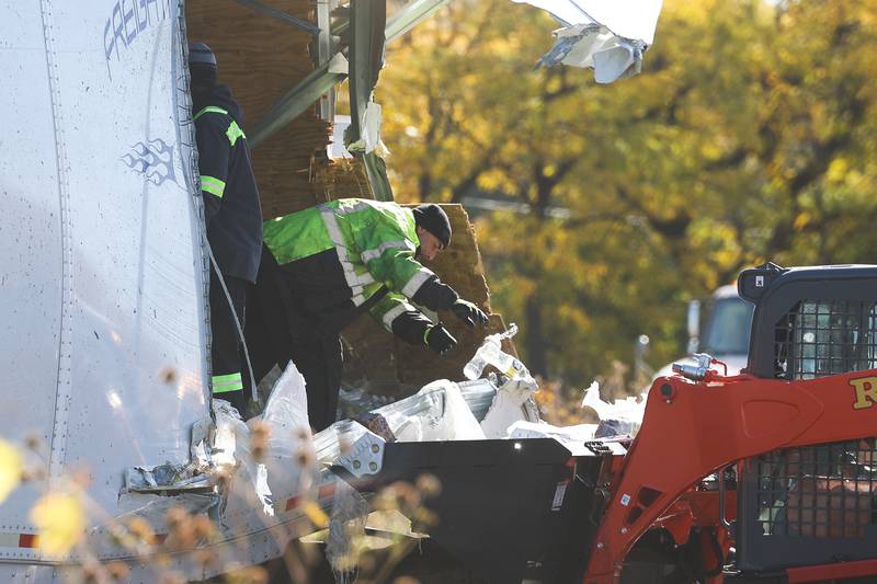 A worker clears water bottles out of a semitrailer. A crash involving two semitrailers shutdown down southbound I-55 as diesel fuel, water bottles and soybeans covered all lanes of Interstate 55 south of the I-80 interchange early Wednesday morning.