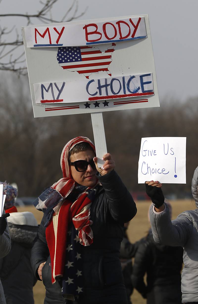 Bonnie Cassel, of Crystal Lake, holds up a choice sign during a Cary School District 26 anti-mask rally Tuesday, Feb. 15, 2022, along Three Oaks Road at Cary Grove Park. The event was attend by about 100 people and organized by the Illinois Parents Union Cary.