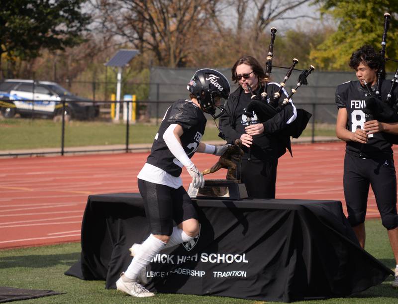 Fenwick football players including Charlie Henrich touch the Heisman Trophy as they enter the field to play the playoff game against Brother Rice Saturday, Nov. 2, 2024.