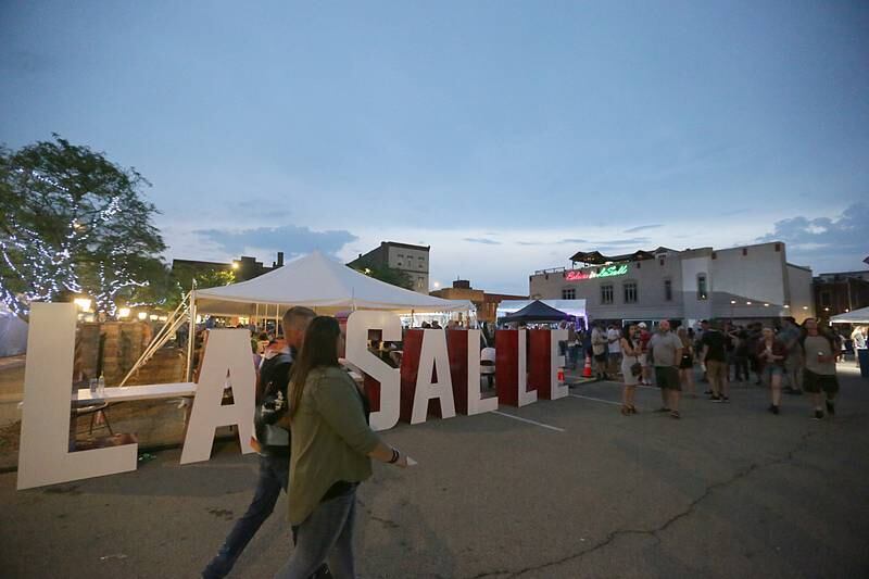 A couple walks past giant letters that spell "La Salle" at the Celebrate La Salle festival on Saturday, June 25, 2022 in La Salle.