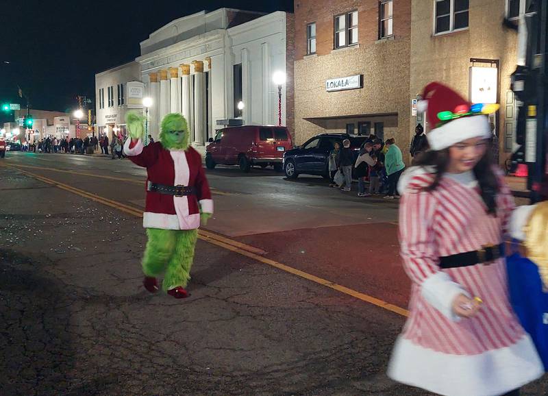 The Grinch waves to parade goers Saturday, Dec. 2, 2023, during the Lighted Christmas Parade in Peru.