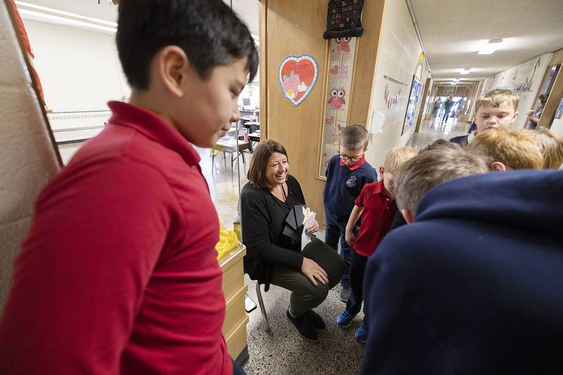 Dixon St. Marys School first-grade teacher Cassie Burgess speaks with students Wednesday, Feb. 1, 2023, during a scavenger hunt at the school. Students were required to find specific teachers and gather information about Catholic saints to complete the game.