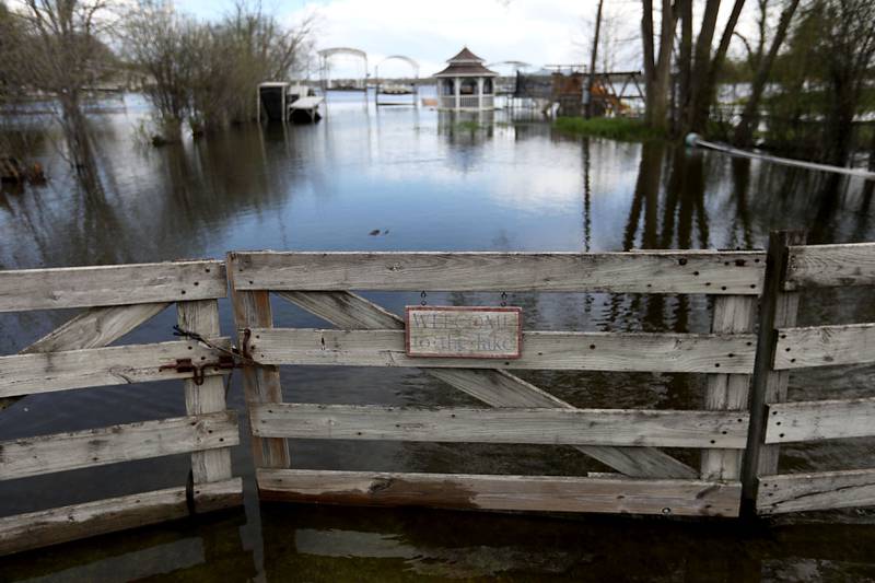 “Welcome to the Lake” sign on the fence of a yard near on Pitzin Road near Lewis Lane on Sunday, April 19, 2026, in Johnsburg, as the Fox River continues to rise.