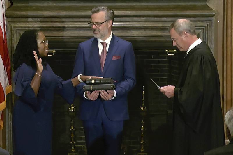 In this image from video provided by the Supreme Court, Chief Justice of the United States John Roberts administers the Constitutional Oath to Ketanji Brown Jackson as her husband Patrick Jackson holds the Bible at the Supreme Court in Washington, Thursday, June 30, 2022. (Supreme Court via AP)