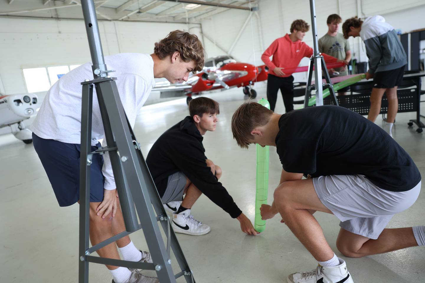 Herscher High School students Gavin Nelson, left, Bryson Schultz, center, and Braedon Pfeiffer participate in a lab as part of the Kankakee Area Career Center's new aviation program held at the Greater Kankakee Airport on Sept. 25, 2025. 
Students worked to achieve enough jet propulsion with balloons and supplies to carry a paper cup along a string from the floor to an overhead target.