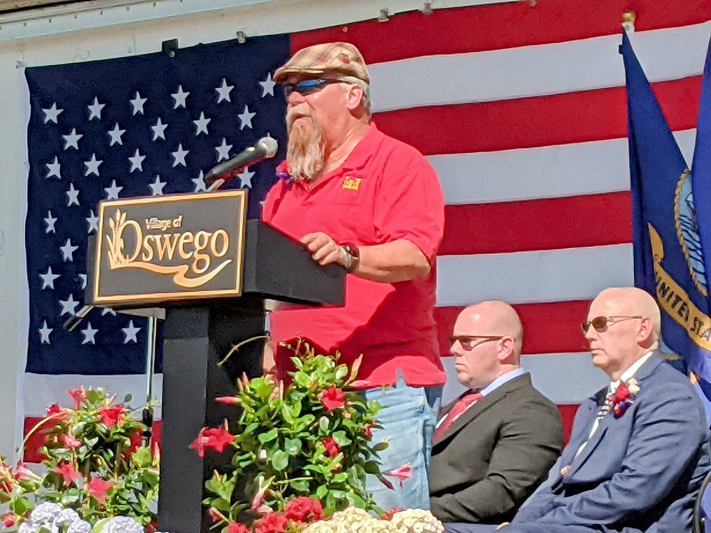 Bob Patterson, father of Chris Patterson, speaks during the May 9 opening ceremony of the Illinois Fallen Wall at Oswego Village Hall. Sitting behind him are Oswego Village President Ryan Kauffman, left, and Kris Kearns, right, a Marine Corps veteran and chairman of Oswego Honors Veterans.