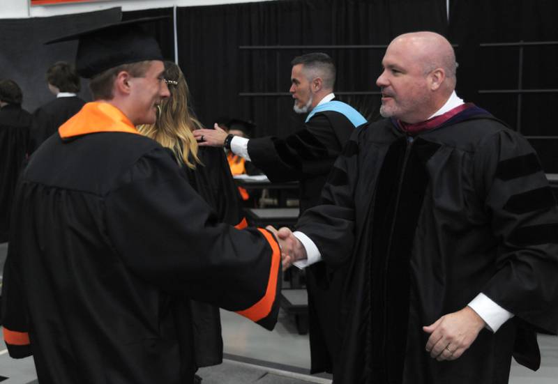 McHenry Community High School District 156 Superintendent Ryan McTague, right, and McHenry High School Principal Jeff Prickett congratulate gradustes Saturday, May 21, 2022, during the McHenry High School’s 102nd Commencement Ceremony in the gym of the school’s Upper Campus. The ceremony was moved inside and split into two ceremonies because of the rainy weather.