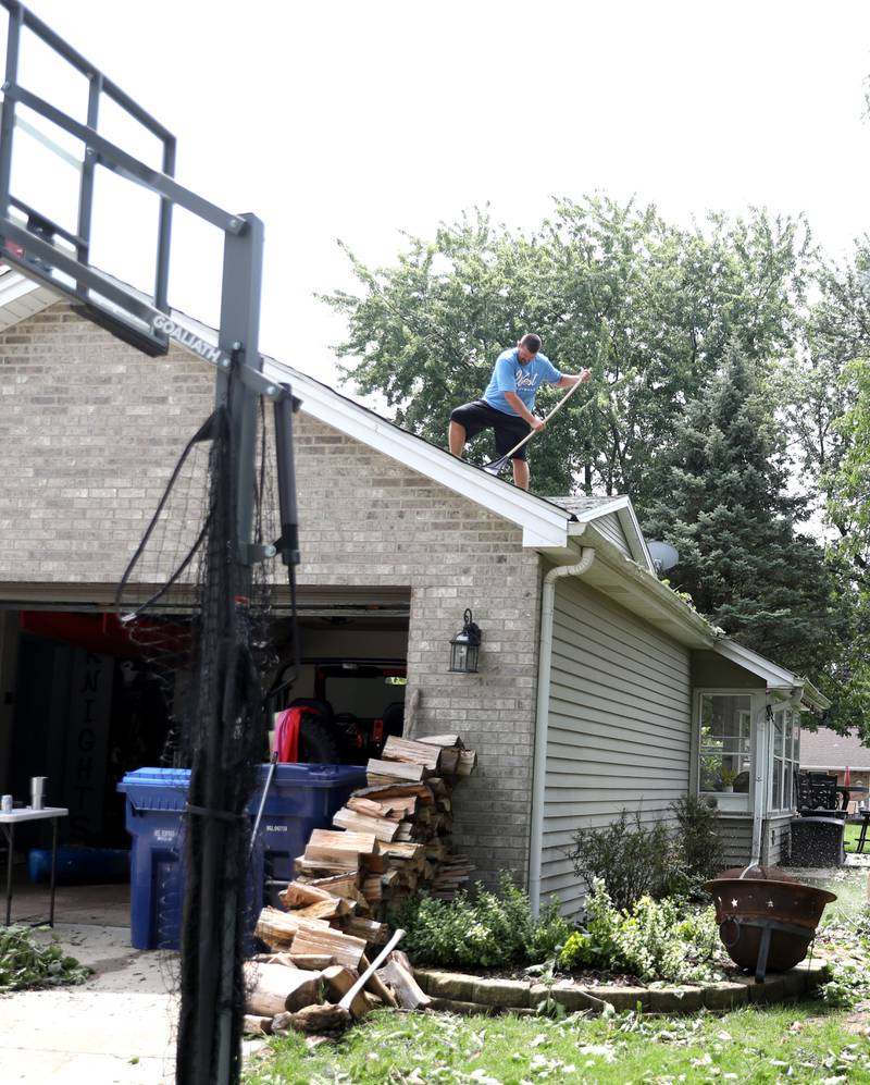 Ryan Crawford clears debris from the roof of his home on Bastian Drive in Sugar Grove following storms ripping through the area the evening of Monday, July 15, 2024.