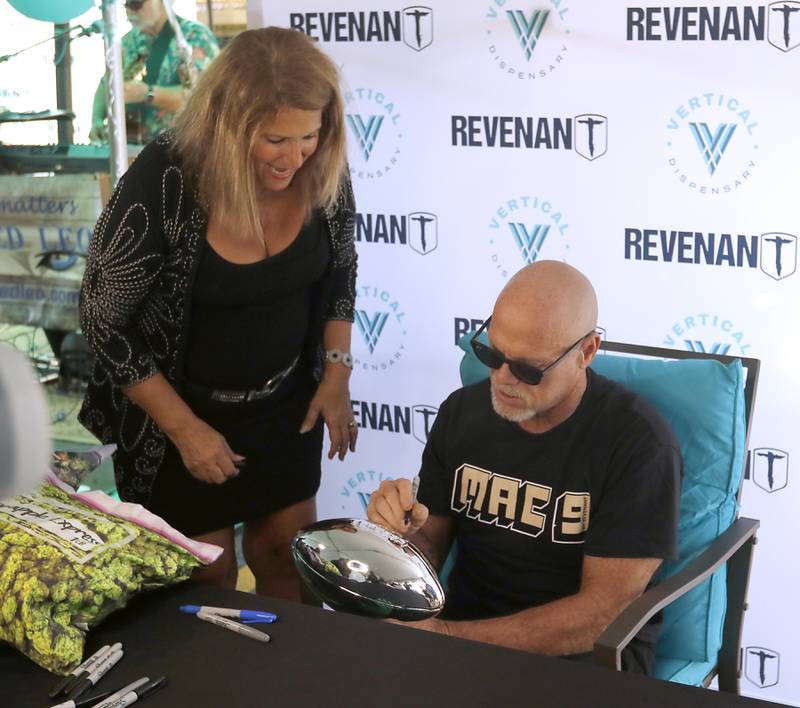 Lorie Rein of Cary talks with former Bears quarterback Jim McMahon as he signs autograph for him during the grand opening of the Vertical Dispensary on Saturday, Sept. 30, 2023, in Cary. The dispensary has been open for about a month.