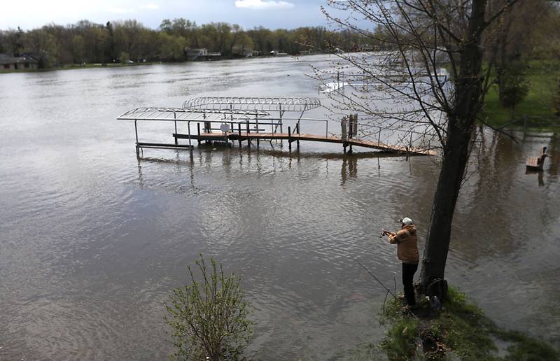 A man fishes in a flooded Francis M. Schmitt Park in Johnsburg on Sunday, April 19, 2026, as the Fox River continues to rise.
