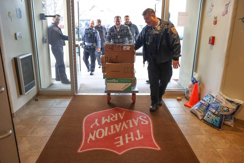 Officer John Perri helps guide a cart of food donations push by Officer Bob Klancher from the police department’s “Pack the Paddy Wagon” food drive at the Salvation Army in Joliet.