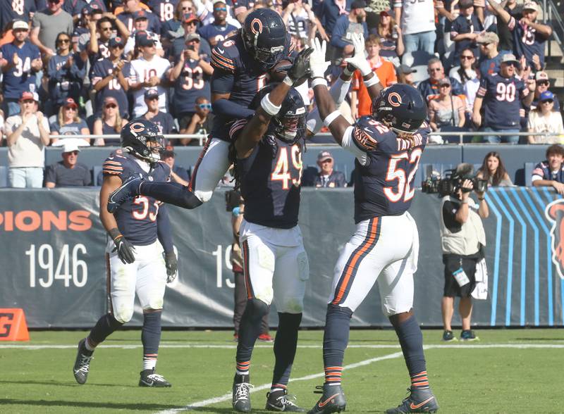 Chicago Bears defensive back Kyler Gordon leaps on the back of teammate linebacker Tremaine Edmunds after picking up a fumble recovery as defensive lineman Darrell Taylor hi-fives him on Sunday, Oct. 6, 2024 at Soldier Field in Chicago.