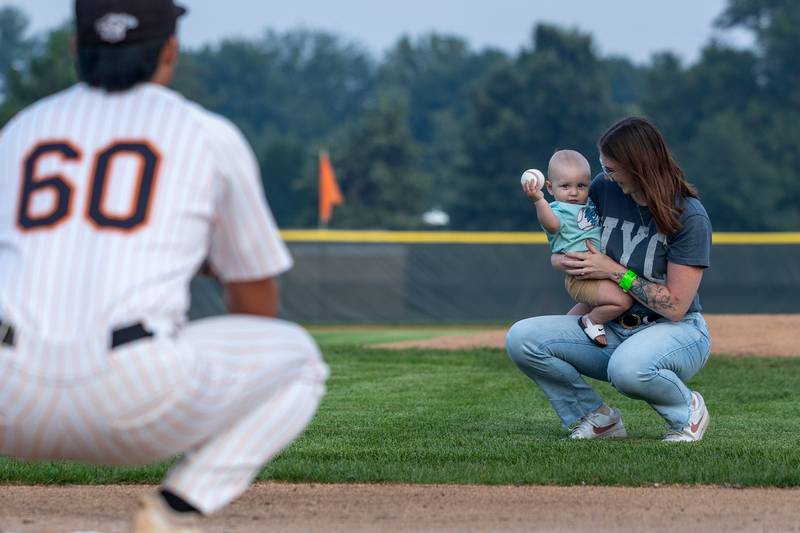 (left to right) Caleb Okada of the Pistol Shrimp catches as Colter Snyder throws the first pitch whilst being held by his mother, Kristin, on Thursday, July 31, 2025, at Schweickert Stadium in Peru.