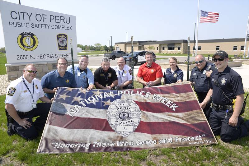 Peru is celebrating National Police Week May 15-21. Showing off their new banner is Police Chief Robert Pyszka, Mayor Ken Kolowski, Blake Frund, Dennis Hocking, Police Lt. Doug Bernabei, Jeff Paul, Christie De Groot, Mark Credi and Nick Biagioni.