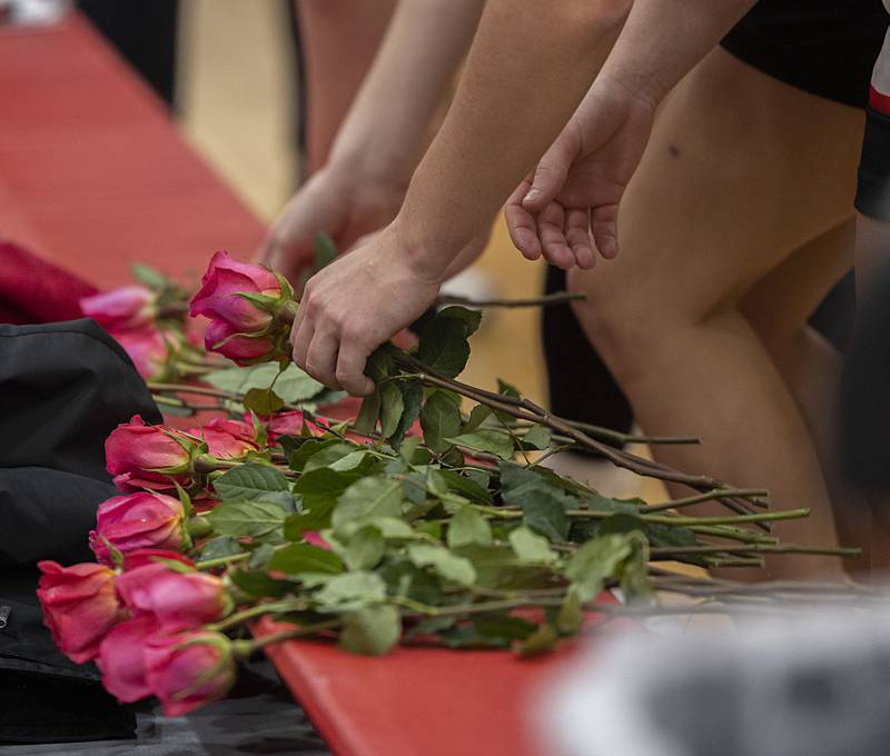 Amboy basketball players pick up roses to present to cancer survivors Tuesday, Jan. 27, 2026, during the Amboy High School Pink Out game and fund raiser. A 50/50 drawing and silent raffle were also held during the night.