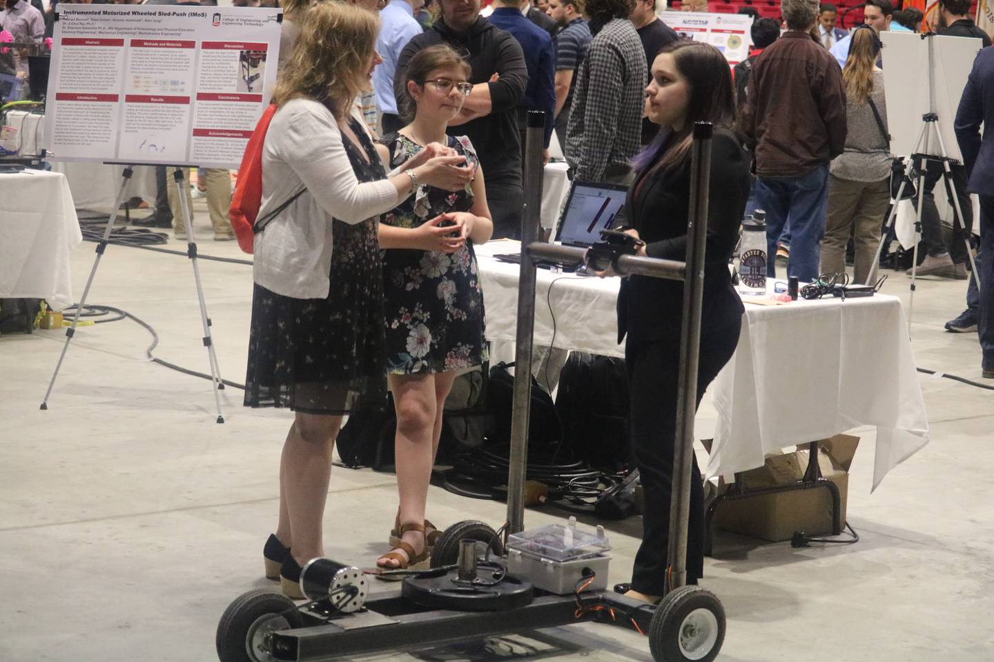 Melinda McGraw (left), Chloe Carpenter and Victoria Jeziorczak (right) huddle around one of the many robots on display at an engineering showcase held May 5, 2023 at the NIU Convocation Center in DeKalb.