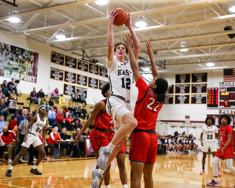 Oswego East's Ryan Johnson (12) shoots a layup over West Aurora's Derrick Mckinney (22) during Class 4A Lockport Regional final game between West Aurora at Oswego East.  Feb 24, 2023.