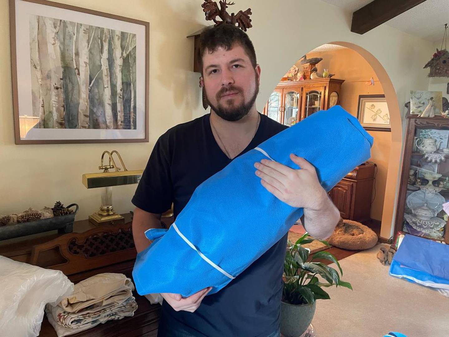 Greg Aimaro holds a waterproof sleeping bag made from expired surgical drapes.  Aimaro and a group of friends recently spent a day making 23 of these sleeping bags.  They have been shipped to Poland and will be distributed to people in Ukraine who need them.