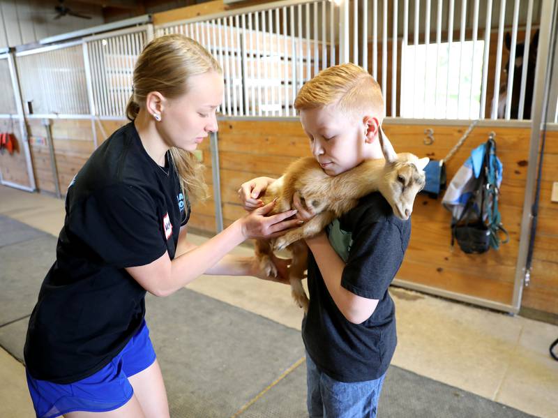 Counselor McKenna Lievrouw helps Jack Lippincott, 14, of Batavia as he holds Nala, a baby goat, during a day camp at the Happy Hooves Therapeutic Farm in Elburn on Monday, June 27, 2022.