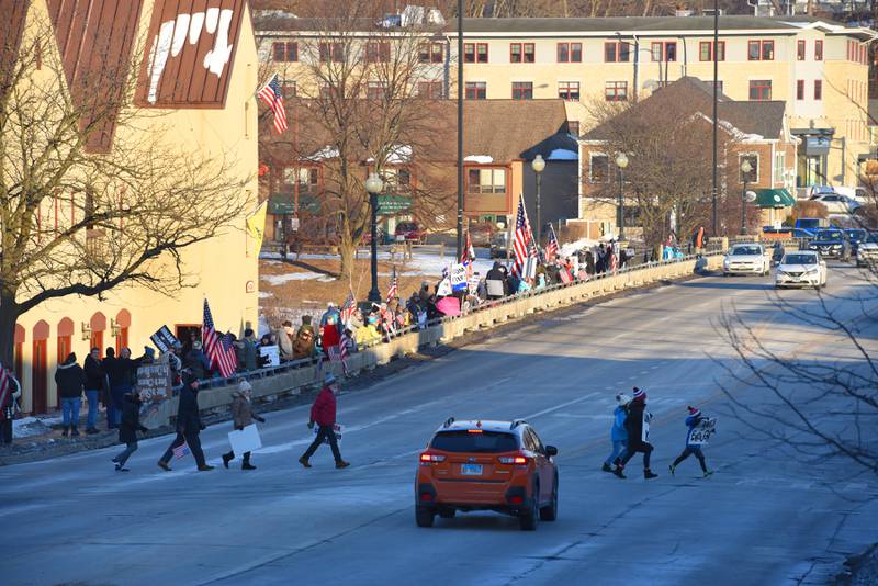About 150 people, including parents and children protest on the State Street Bridge over the Fox River in Geneva. Masks will be optional beginning Feb. 8.