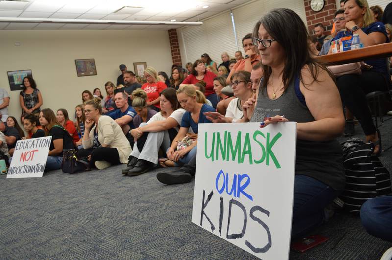 About 100 people, including Kari Cross, far right, crowd into the Huntley School District 158 school board meeting Thursday, July 15, 2021, to support dozens of people who spoke to the board, urging it to give students the option to not wear masks regardless of whether they've been vaccinated against COVID-19, for the upcoming school year.