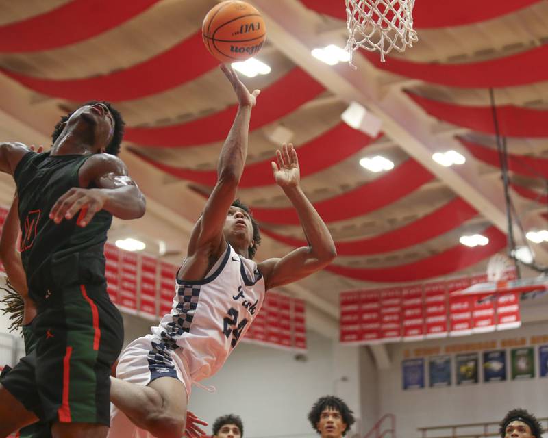 Oswego East's Dshaun Bolden (24) flips up a shot while falling away from the basket during their Hinsdale Central Holiday Classic basketball game between Morgan Park at Oswego East Saturday, Dec 27, 2025 in Hinsdale.