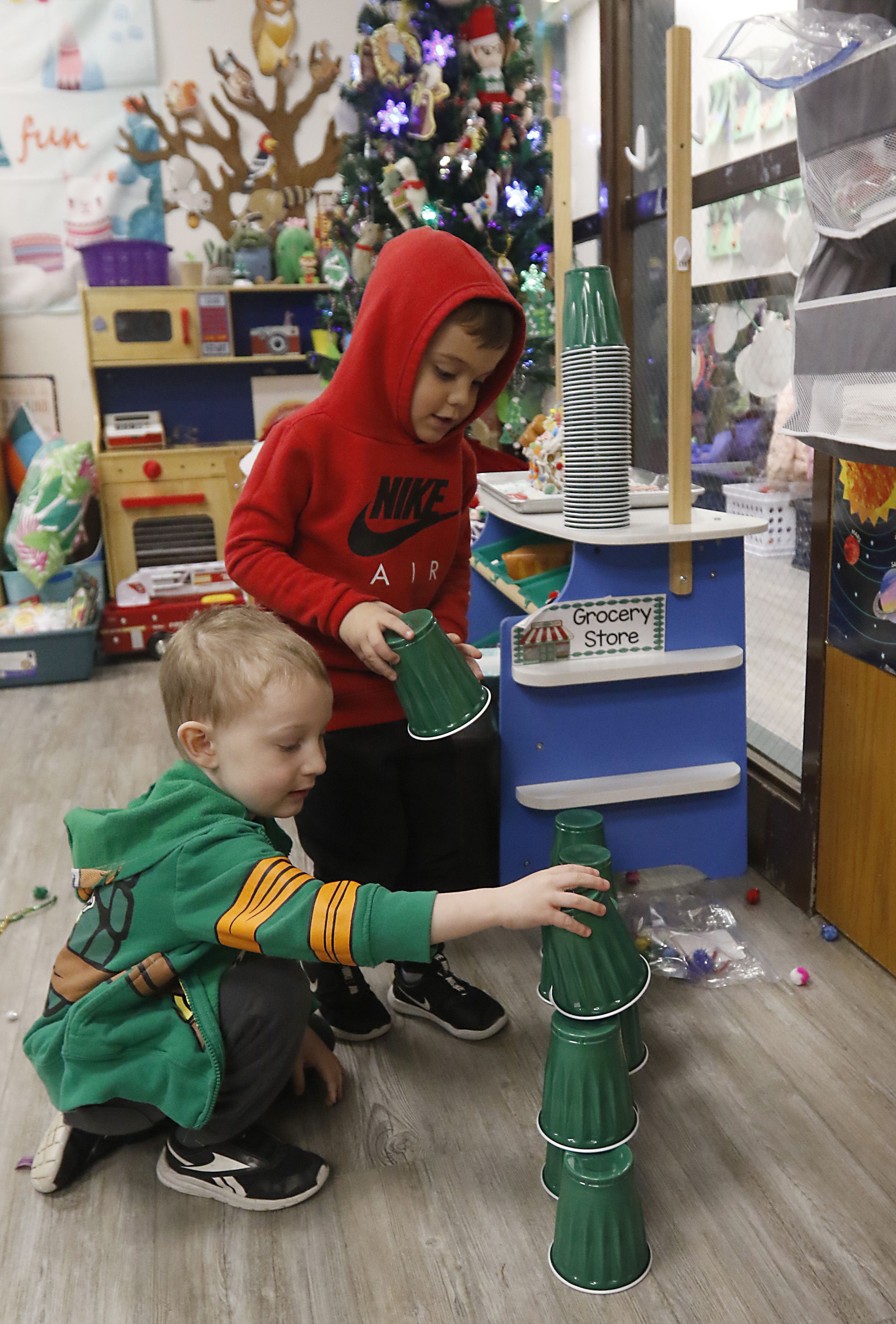 Charlie Enright and Jacob Aguilera make a Christmas tree out of green cups on Thursday, Dec. 14, 2023, during their class at the Zion Lutheran Church and School in McHenry.
