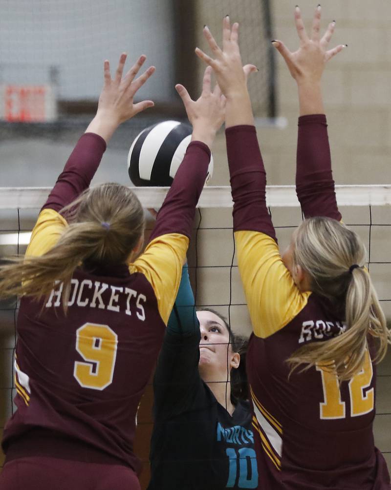 Woodstock North's Ava Kardaras (center) tries to tip the ball throw the block of Richmond-Burton's Reagan Wisniewski (left)  and Zoe Freund (right) during a Kishwaukee River Conference volleyball match on Monday, Sept. 15, 2025, at the Woodstock North High School.