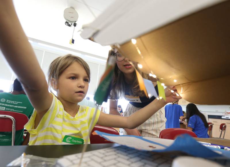 Gracie P. strings lights on the roof of her pop-up venture with the help of Maggie W.  during Camp Invention at Central Intermediate School on Thursday, June 15, 2023 in Ottawa. Students produced their own pop-up shop, making decisions and using original strategies to attract customers with the ultimate block party. Children communicated through marketing and advertising, learning how to launch and operate their own venture.