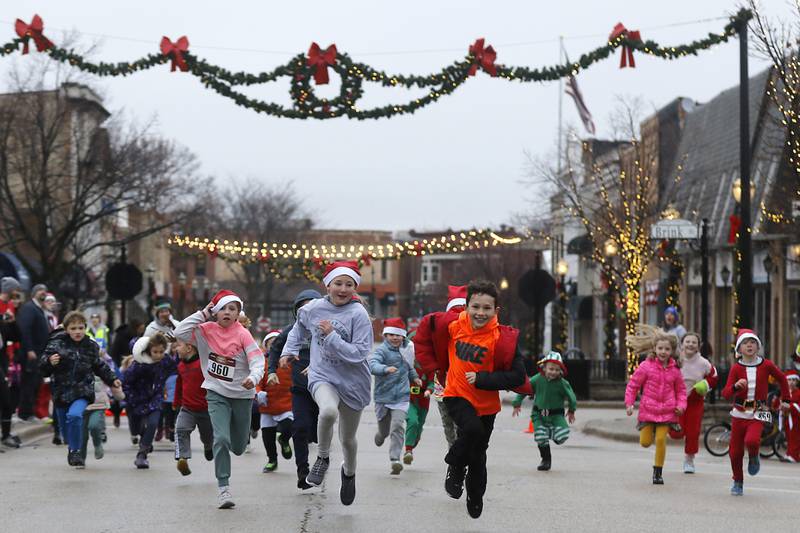 Children spring to the finish line in during the kids 50-yard dash during the McHenry County Santa Run For Kids on Sunday morning, Dec. 3, 2023, in Downtown Crystal Lake. The annual event raises money for agencies in our county who work with children in need.