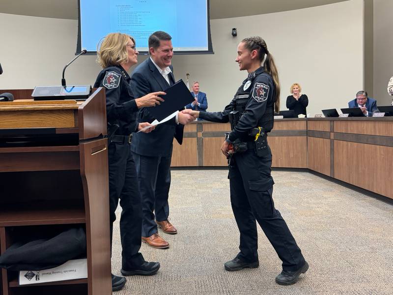 2023 Officer of the Year Sarah Markusic shakes hands with Morris Mayor Chris Brown and Morris Police Chief Alicia Steffes.