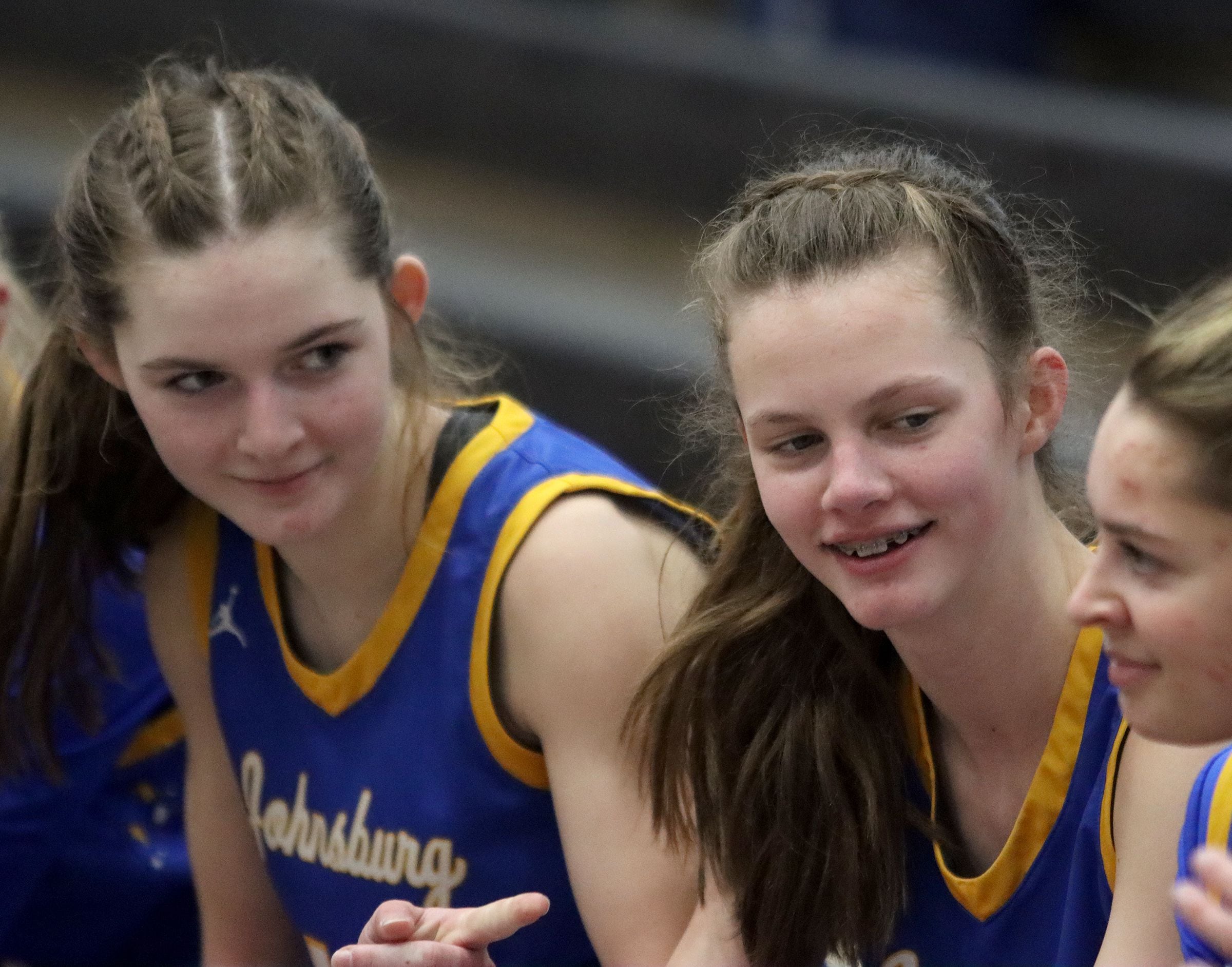 Johnsburg’s Summer Toussaint (left) and Skye Toussaint meet with teammates during a timeout last season in a game at McHenry High School.