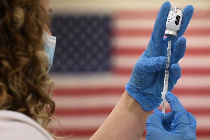 Crista Mundil, a nursing student at McHenry County College and volunteer at the COVID-19 vaccination clinic at Huntley High School, fills a syringe with the Moderna  COVID-19 vaccine on Friday, March 12, 2021 in Huntley.