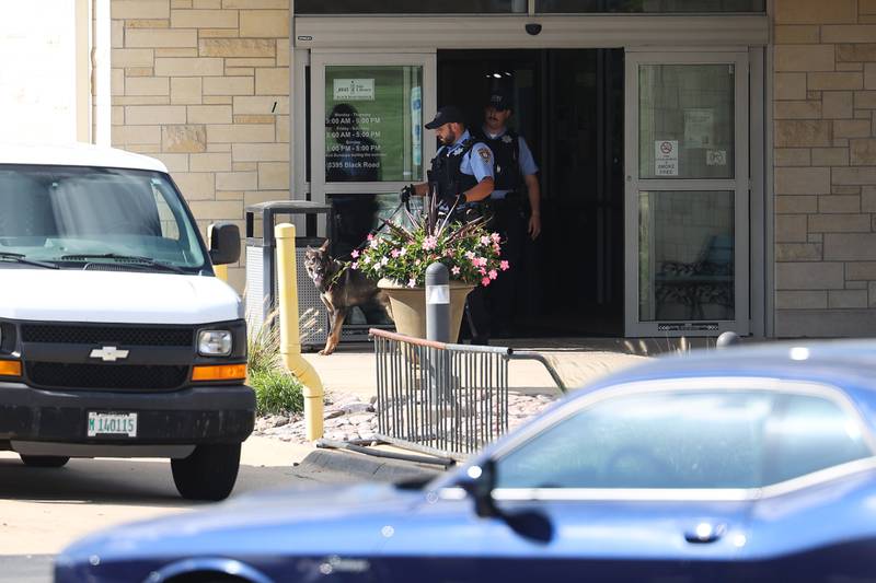 A K9 unit exits the Black Road Branch Library after a bomb threat at that location on Thursday, Sept. 14, in Joliet.