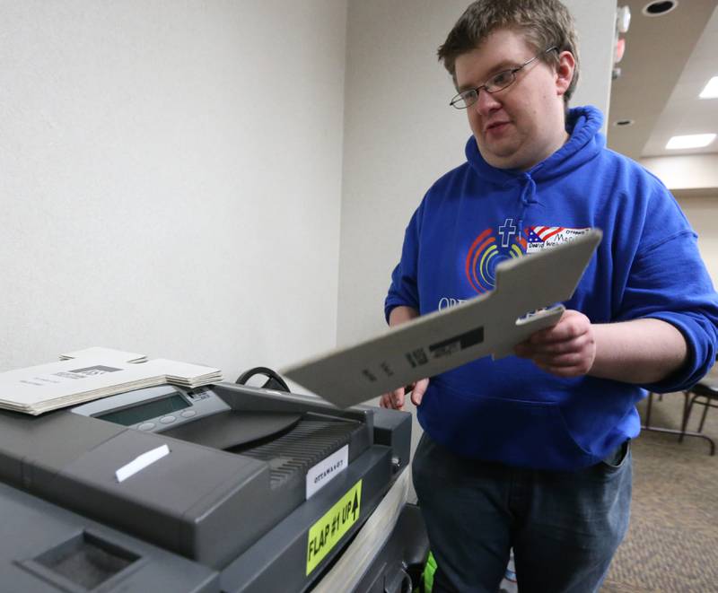 Marshall Wahlstrom Helgren helps a voter cast a ballot at the Knights of Columbus Hall on Tuesday, April 4, 2023 in Ottawa.