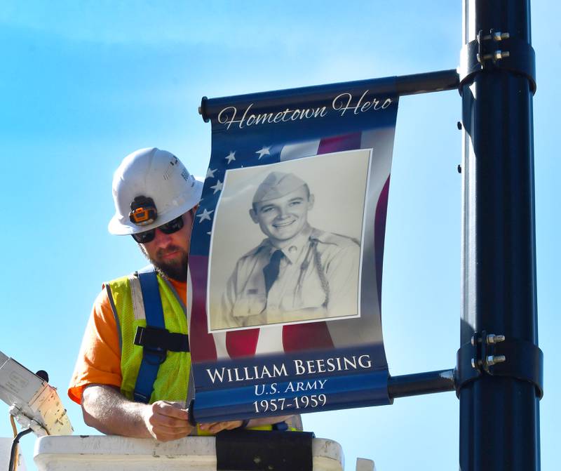 Oregon Public Works employee Josh Pickering adjusts a veteran banner featuring William Beesing on a city light pole in downtown Oregon on Thursday, April 23, 2026. Beesing was in the Army from 1957-1959.