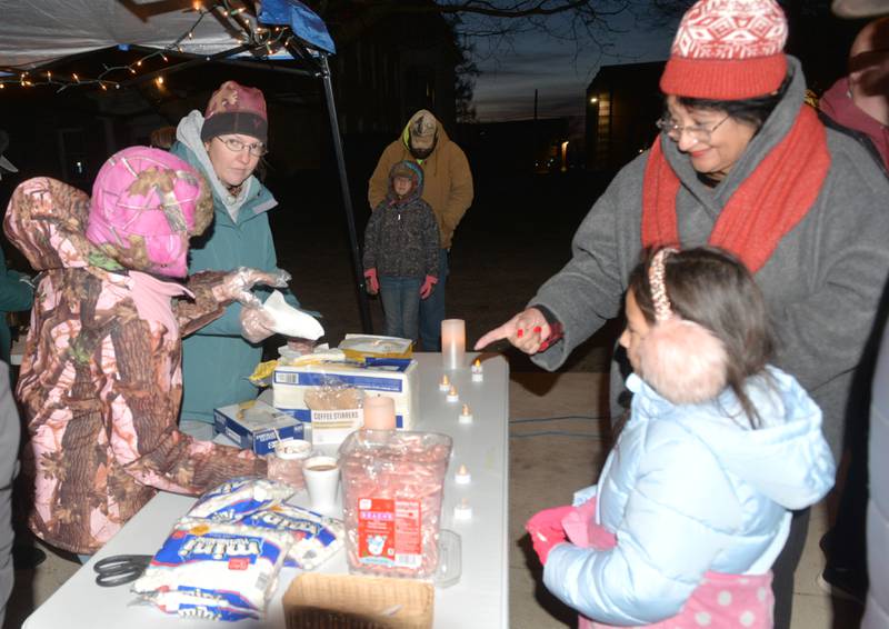 Members of the Free Evangelical Church of Mt. Morris serve hot chocolate and hot cider to Chella Hey, 7, and Angelina Delhital, of Dixon, during Mt. Morris' Christmas in the Village on Saturday, Dec. 7, 2024.