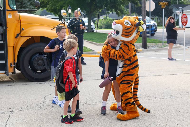 Herscher Intermediate School student Elany Quinones, right, receives a hug from the Tigers mascot as she arrives for her first day of fourth grade on Tuesday, Aug. 19, 2025.