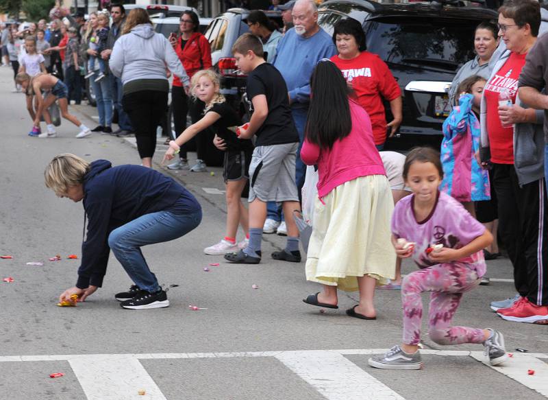 Children along with adults scamper for candy treats Tuesday evening during Ottawa Township High School’s Homecoming Parade.