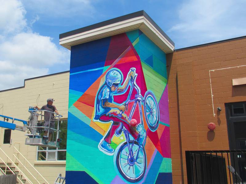 Jason Watts with his nearly complete mural in the alley at 59 Main St. in downtown Oswego.
