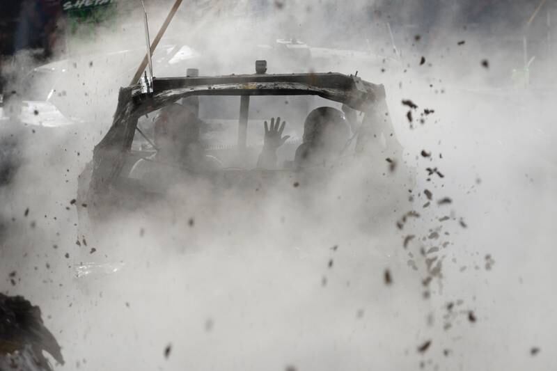 A passenger reacts to a hit as he and his driver fight off smoke and mud at the Whiteside County Fair's demolition derby on Saturday, Aug. 17, 2024.