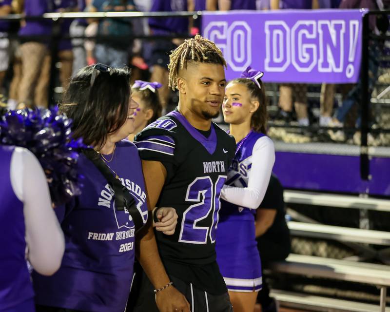 Downers Grove North's Noah Battle (20) is escorted by his mother during homecoming ceremonies.  He did not play due to an injured ankle.  Sept 29, 2023.