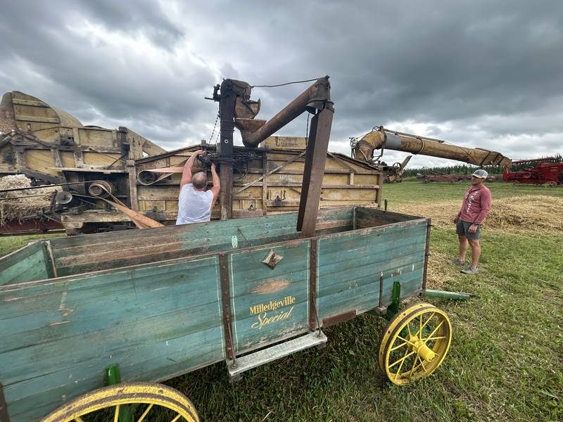 A volunteer reaches to adjust a belt and pulley on a threshing machine at the Bos Brothers Historical Farm south of Erie on Saturday, July 26, 2025.