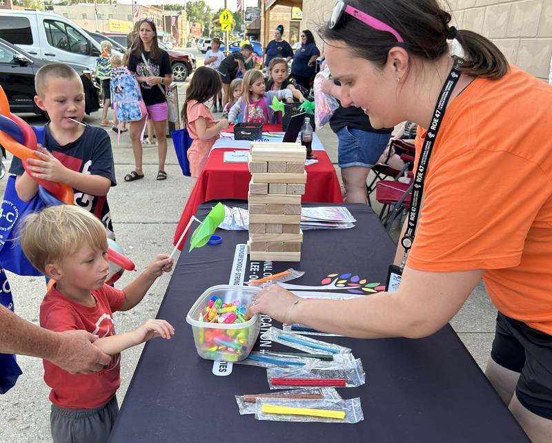 Bentley Hall, 3, of Lyndon, visits with Grace Heimerdinger-Baake, of the Regional Office of Education 47, during Prophetstown's Fourth Friday on Friday, July 26, 2024. The ROE was one of the entities that handed out school supplies and other items during the event.