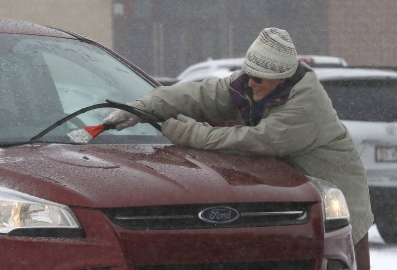 Teacher Leah Diane Kane cleans the windows of her car on Thursday, Feb. 16, 2023, at Richmond-Burton Community High School in Richmond, after a winter storm moved through McHenry County creating hazardous driving conditions.
