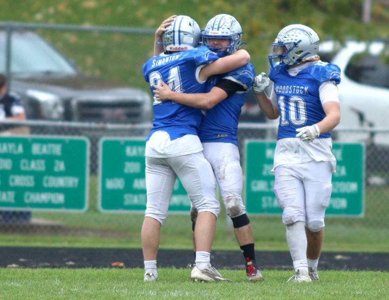 Woodstock’s Maximus Miller is greeted in the end zone by teammates Jack Simonton (24) and Landen Stoltz (10) after a lengthy Miller touchdown run in the fourth quarter against Ottawa in