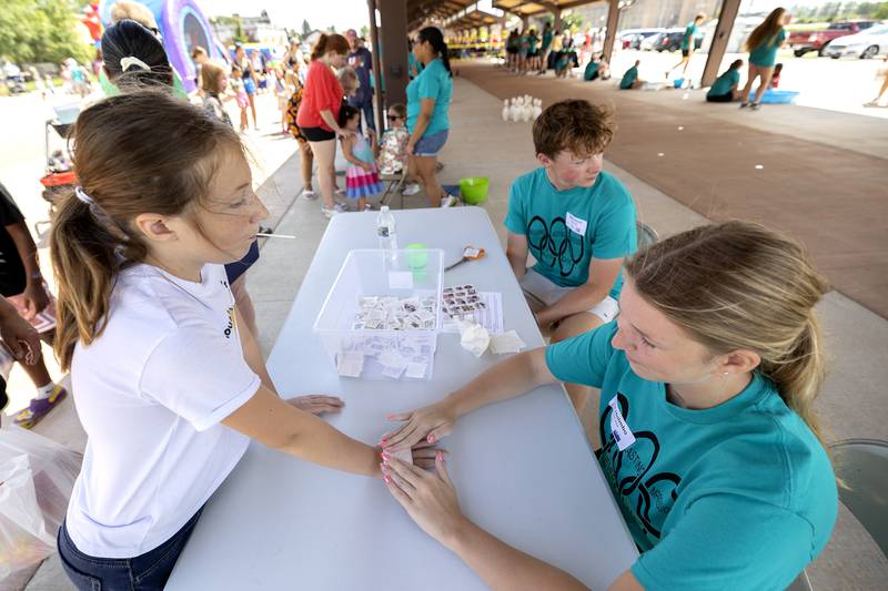 Raegan Prescott, 9, of Sterling gets a new, yet temporary, tattoo by Building Lasting Impressions that Never Die (BLIND) leader Ella Holmbo of Fulton on Friday, Aug. 2, 2024.