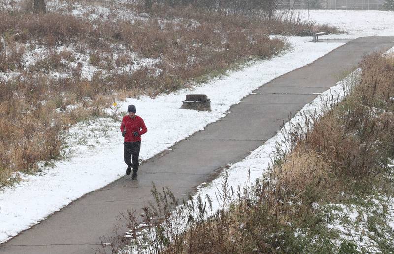 A jogger braves the elements as he runs on the the DeKalb Nature Trail along the Kishwaukee River Tuesday, Nov. 15, 2022, near Hopkins Park in DeKalb. Tuesday was the first measurable snowfall in DeKalb County this season.