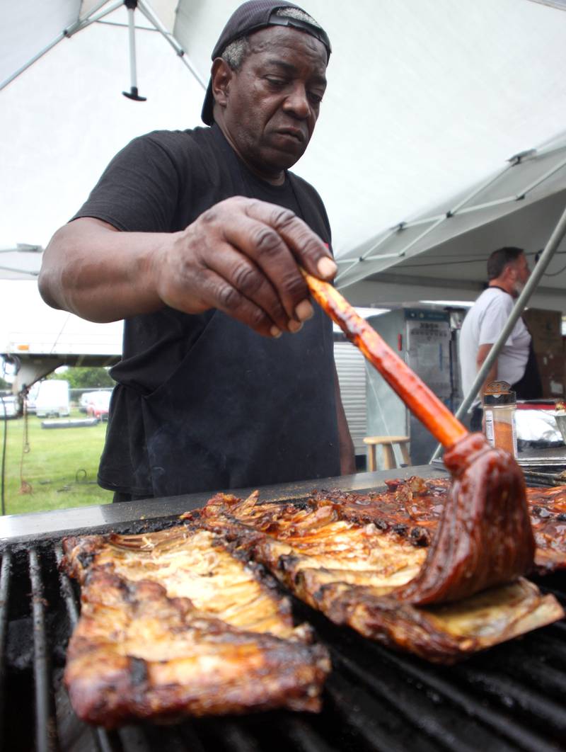 Frank Gary slathers ribs at the Pigfoot booth during the Rockin’ Rib Fest Friday at Sunset Park in Lake in the Hills.